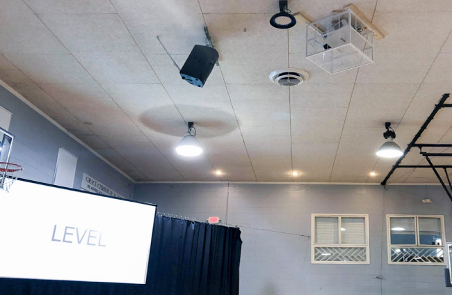 Проекторы Maxell в помещении Центра Милосердия: «Мы сделали заказные металлические клетки для защиты проекторов в течение недели пока обучающиеся используют пространство как спортивный класс», - говорит Хайнес. «Данные клетки закреплены к потолку с проекторами. И полностью защищают наши проекторы, но оставляют доступ к самому оборудованию.»